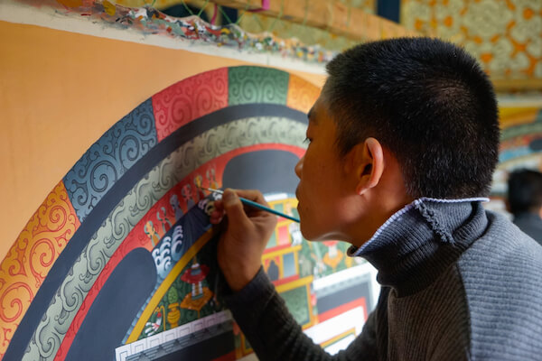 Young man refreshes the paint in a Bhutanese temple - image by Angela Maier/shutterstock.com