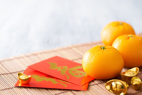 Chinese New Year red packets and oranges - image: shurtterstock.com