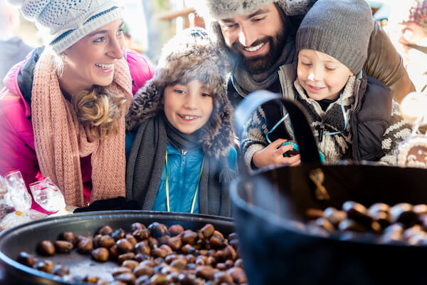 Family with two children holding maroni chestnuts at christmas market - image by shutterstock