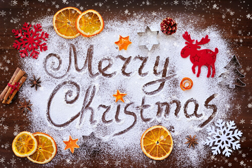 Merry Christmas food theme - written in icing sugar with orange slices and cinnamon sticks