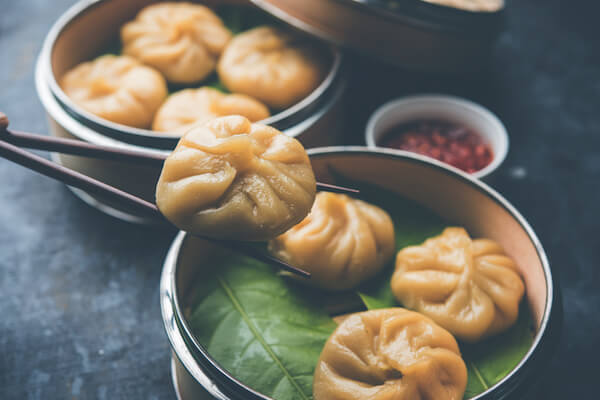 Nepalese momos with achar sauce in bowl with chopsticks