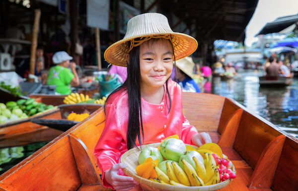 Typical floating market in Thailand - girl presenting fruits in basket