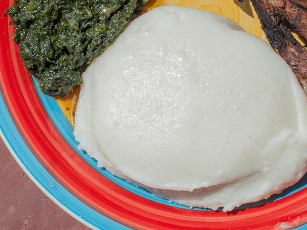 South African mieliepap on plate with morogo spinach and piece of meat
